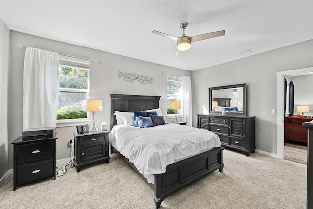 bedroom with multiple windows, light carpet, baseboards, and ceiling fan