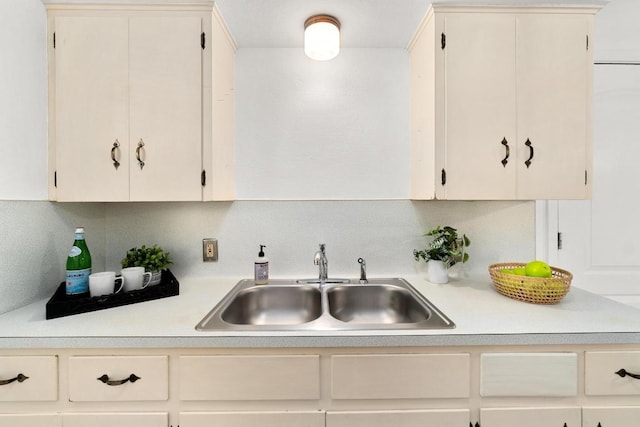 kitchen with a sink, light countertops, and backsplash