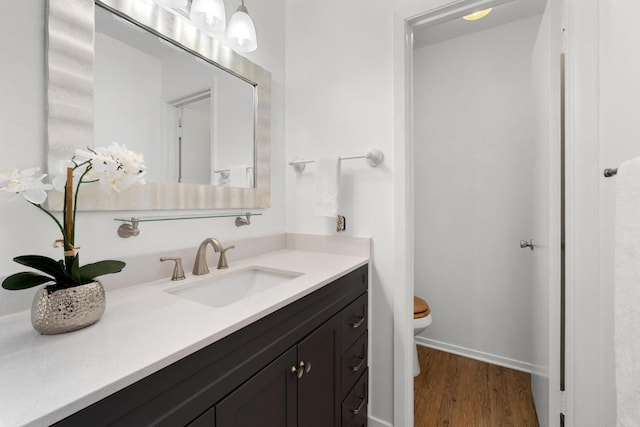 bathroom featuring vanity, toilet, wood finished floors, and baseboards