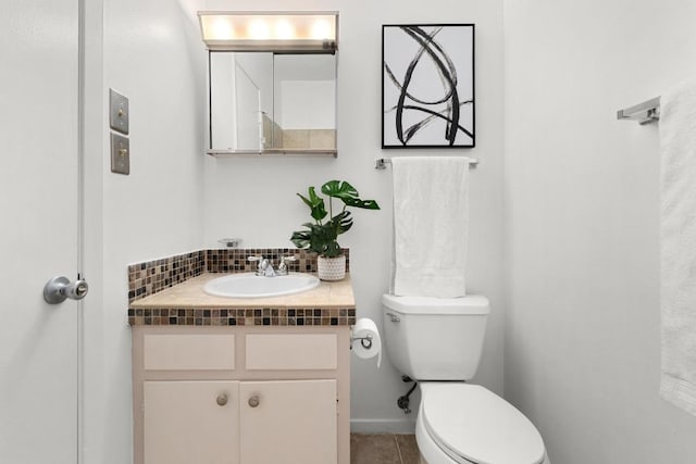 half bath featuring toilet, vanity, and tile patterned flooring