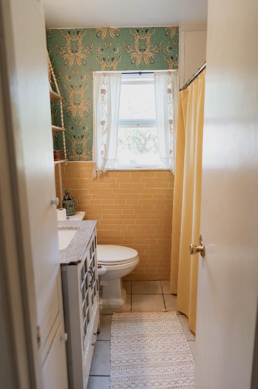 1305 Larkspur Rd, Austin, TX 78758 - full bathroom with tile patterned flooring, wainscoting, toilet, tile walls, and vanity