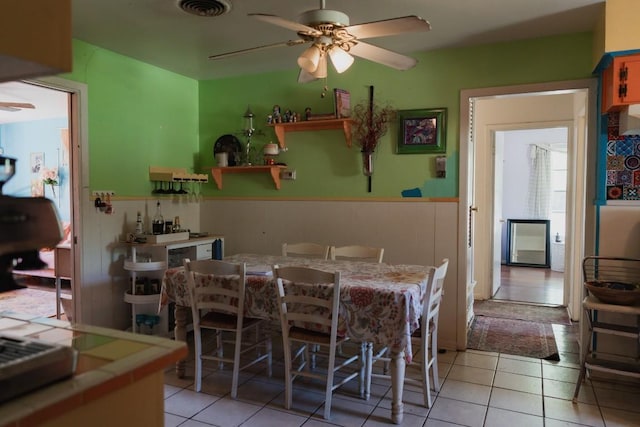 1305 Larkspur Rd, Austin, TX 78758 - dining room with a wainscoted wall, a ceiling fan, and light tile patterned flooring