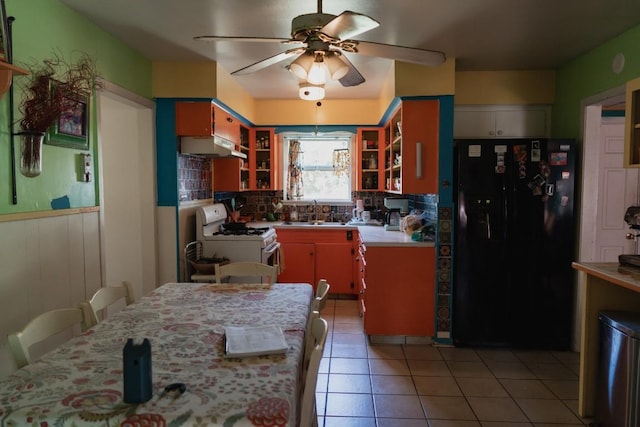 1305 Larkspur Rd, Austin, TX 78758 - kitchen featuring black refrigerator with ice dispenser, white range with gas stovetop, light countertops, a sink, and under cabinet range hood
