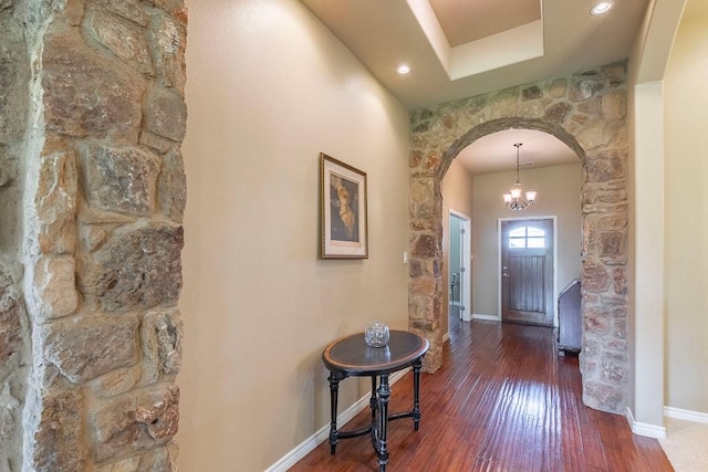 foyer featuring arched walkways, hardwood / wood-style floors, baseboards, recessed lighting, and a chandelier