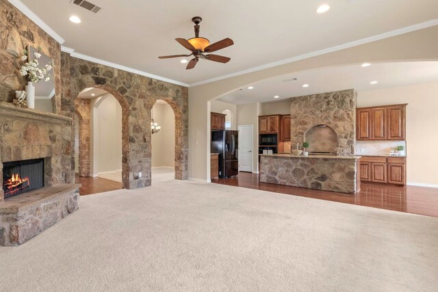 15105 General Williamson Dr, Austin, TX 78734 - unfurnished living room featuring arched walkways, a fireplace, dark colored carpet, a ceiling fan, and ornamental molding