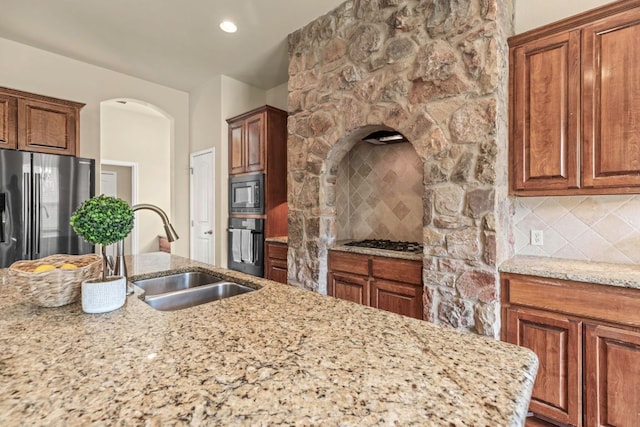 15105 General Williamson Dr, Austin, TX 78734 - kitchen featuring appliances with stainless steel finishes, tasteful backsplash, light stone counters, and brown cabinets