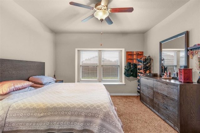 bedroom with light colored carpet, multiple windows, baseboards, and ceiling fan