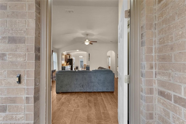 living area with arched walkways and ceiling fan