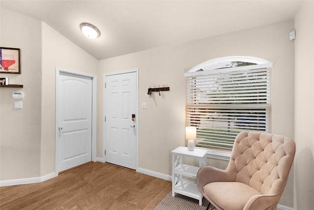 sitting room with vaulted ceiling, wood finished floors, healthy amount of natural light, and baseboards