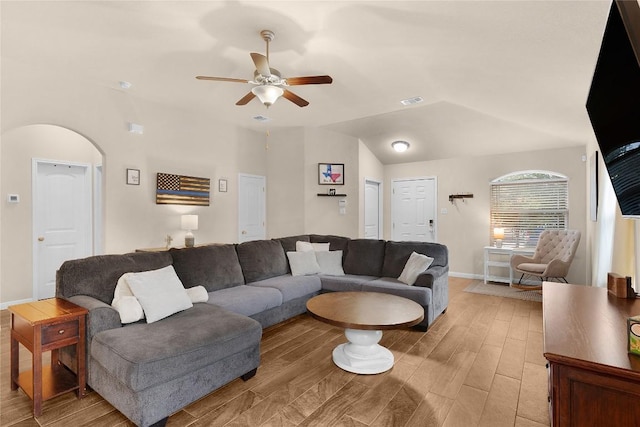 living room with a ceiling fan, light wood-style flooring, baseboards, and vaulted ceiling