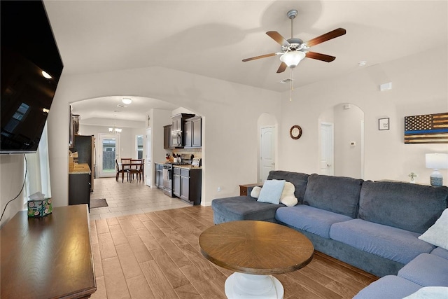 living area with arched walkways, ceiling fan, and light wood-type flooring