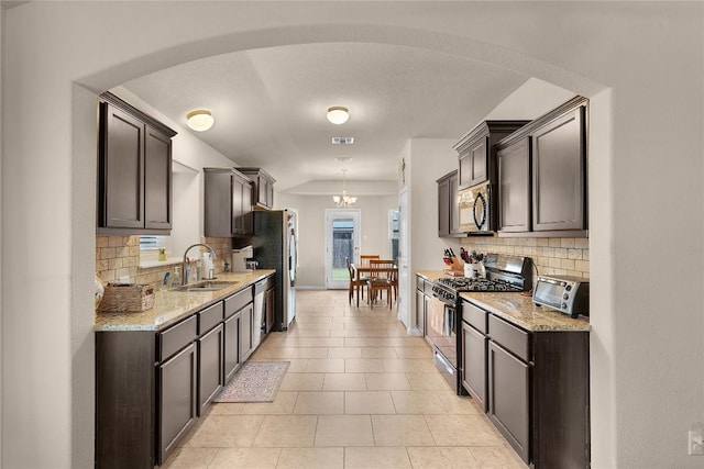 kitchen with stainless steel appliances, a sink, decorative backsplash, and dark brown cabinets