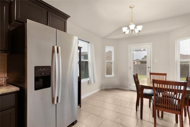 dining room with a chandelier, baseboards, light tile patterned floors, and vaulted ceiling