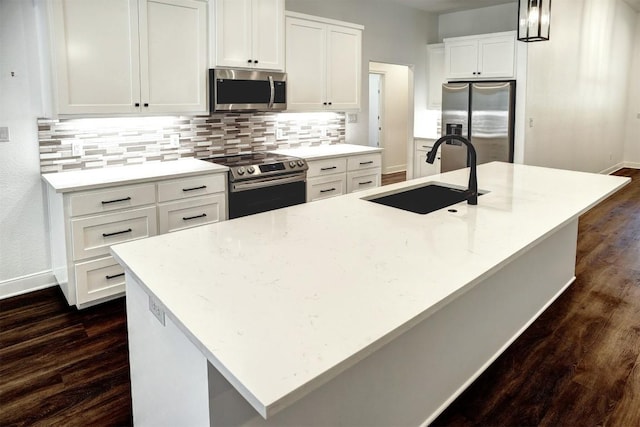 102 Kaena Ln, Bastrop, TX 78602 - kitchen featuring appliances with stainless steel finishes, dark wood-style floors, decorative backsplash, a kitchen island with sink, and white cabinets