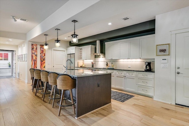 3200 Grandview St Unit 15, Austin, TX 78705 - kitchen with wall chimney range hood, light wood-style flooring, white cabinets, and recessed lighting