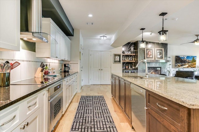 3200 Grandview St Unit 15, Austin, TX 78705 - kitchen featuring stainless steel appliances, a sink, wall chimney exhaust hood, open floor plan, and white cabinets