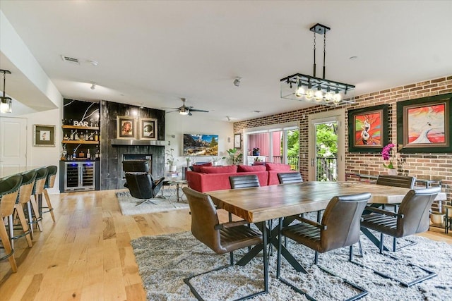 3200 Grandview St Unit 15, Austin, TX 78705 - dining area featuring brick wall, light wood-type flooring, a fireplace, wine cooler, and ceiling fan
