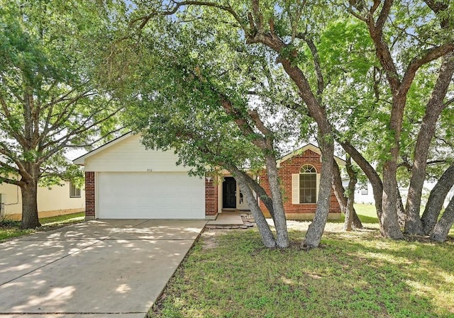 view of property hidden behind natural elements featuring concrete driveway, brick siding, an attached garage, and a front yard