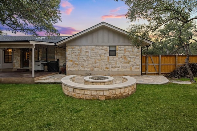 701 W Esparada Dr, Georgetown, TX 78628 - back of property at dusk with stone siding, a patio, an outdoor fire pit, and a shingled roof