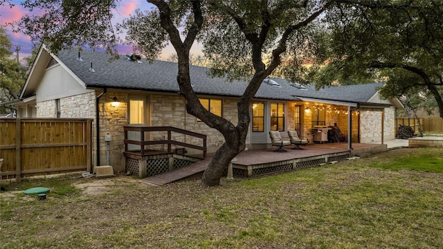 701 W Esparada Dr, Georgetown, TX 78628 - back of house at dusk with stone siding, a shingled roof, and a wooden deck