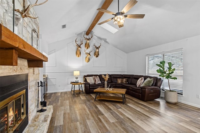 701 W Esparada Dr, Georgetown, TX 78628 - living room featuring wood finished floors, ceiling fan, a glass covered fireplace, and a skylight