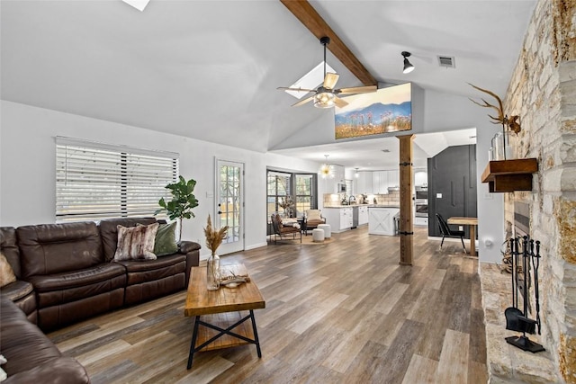 701 W Esparada Dr, Georgetown, TX 78628 - living area with a ceiling fan, a stone fireplace, wood finished floors, beamed ceiling, and high vaulted ceiling