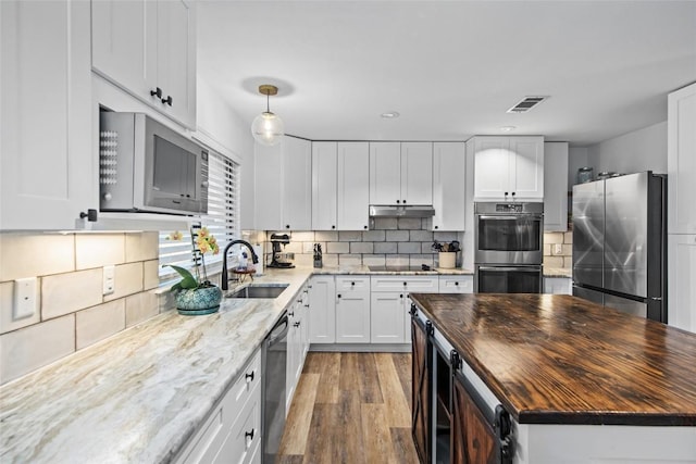 701 W Esparada Dr, Georgetown, TX 78628 - kitchen with appliances with stainless steel finishes, butcher block counters, wood finished floors, a sink, and white cabinetry