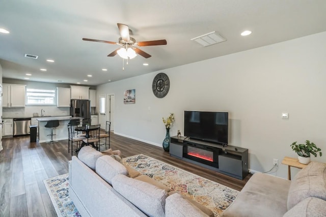 12003 Corsicana Trl, Manor, TX 78653 - living area with a ceiling fan, dark wood finished floors, recessed lighting, a glass covered fireplace, and baseboards