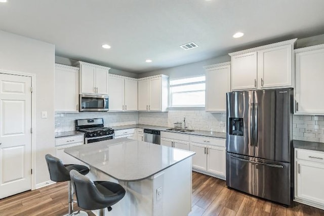 12003 Corsicana Trl, Manor, TX 78653 - kitchen featuring appliances with stainless steel finishes, a sink, a breakfast bar area, backsplash, and white cabinets