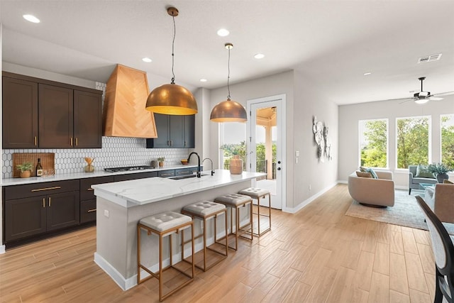 324 Pisa Ln, Georgetown, TX 78628 - kitchen with a sink, backsplash, open floor plan, premium range hood, and baseboards
