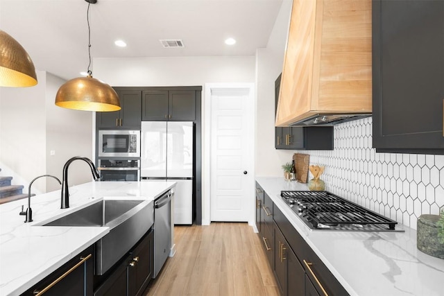 324 Pisa Ln, Georgetown, TX 78628 - kitchen featuring stainless steel appliances, a sink, premium range hood, decorative backsplash, and pendant lighting