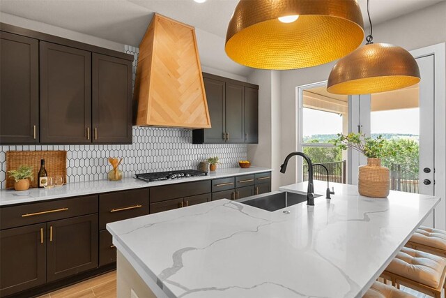 324 Pisa Ln, Georgetown, TX 78628 - kitchen featuring a sink, stainless steel gas stovetop, light wood-style floors, decorative backsplash, and a kitchen bar