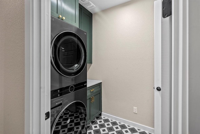 324 Pisa Ln, Georgetown, TX 78628 - washroom featuring estacked washer and dryer, cabinet space, baseboards, and tile patterned floors