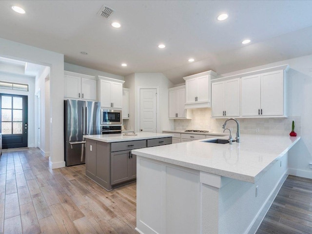 kitchen featuring a sink, stainless steel appliances, baseboards, light wood-style floors, and recessed lighting