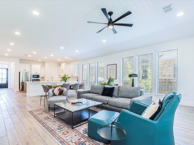 living room featuring light wood-type flooring, recessed lighting, ceiling fan, and baseboards