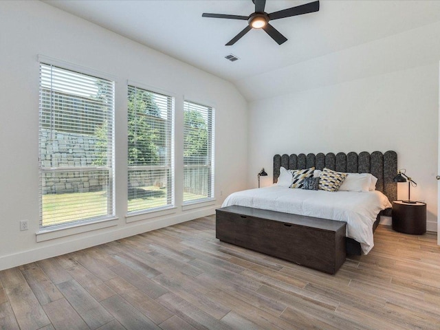 bedroom featuring light wood finished floors, lofted ceiling, ceiling fan, and baseboards