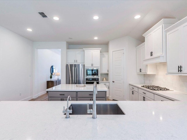 kitchen with stainless steel appliances, a sink, recessed lighting, decorative backsplash, and white cabinetry