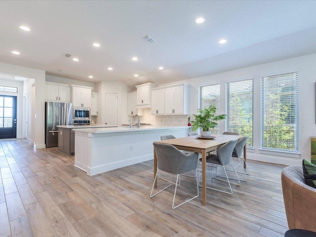 kitchen featuring stainless steel appliances, light wood finished floors, light countertops, a sink, and recessed lighting