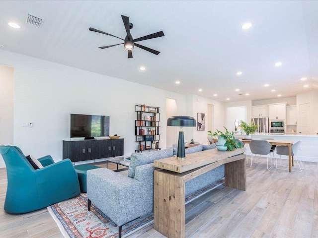 living room with light wood-type flooring, a ceiling fan, and recessed lighting