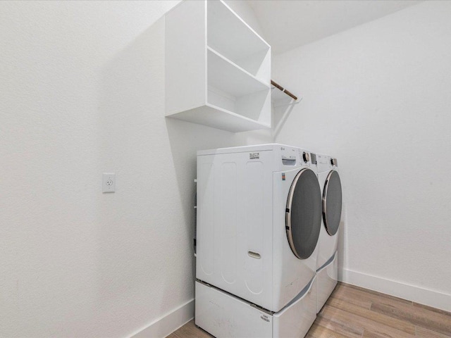 laundry room featuring washing machine and dryer, baseboards, and light wood-style floors