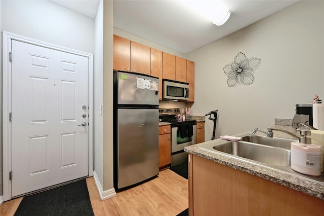 2502 Leon St Unit 213, Austin, TX 78705 - kitchen featuring appliances with stainless steel finishes, a sink, light wood-style flooring, and brown cabinets