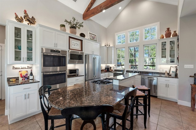 12316 Triple Creek Dr, Dripping Springs, TX 78620 - kitchen featuring appliances with stainless steel finishes, high vaulted ceiling, white cabinets, glass insert cabinets, and a kitchen island