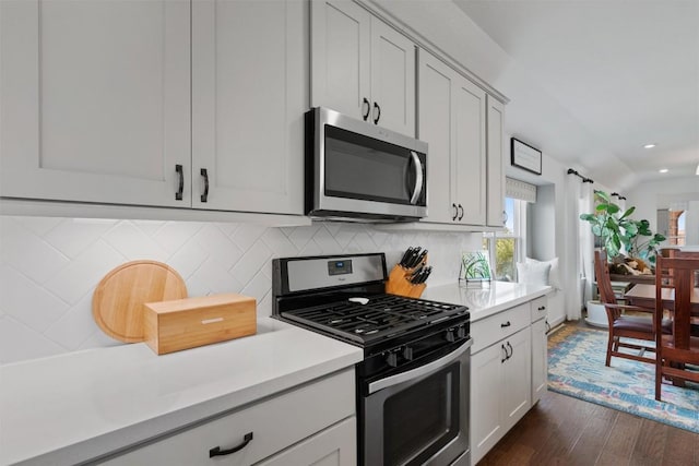 kitchen featuring appliances with stainless steel finishes, light countertops, dark wood finished floors, recessed lighting, and decorative backsplash