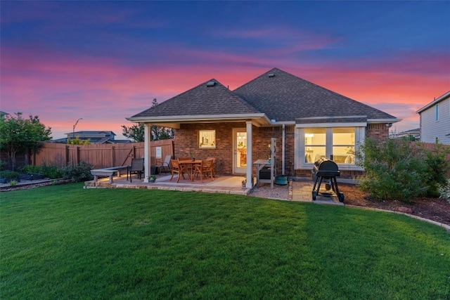 back of property at dusk with a patio area, brick siding, and a shingled roof