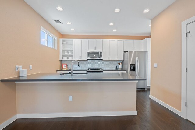 3105 Aldwyche Dr, Austin, TX 78704 - kitchen featuring stainless steel appliances, a sink, a peninsula, white cabinets, and decorative backsplash