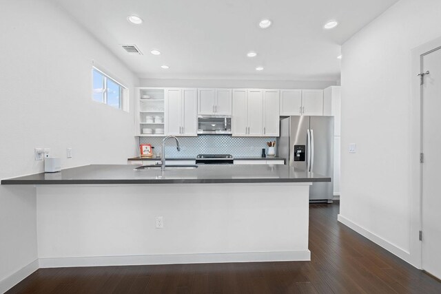 3105 Aldwyche Dr, Austin, TX 78704 - kitchen with stainless steel appliances, a sink, a peninsula, white cabinets, and dark countertops