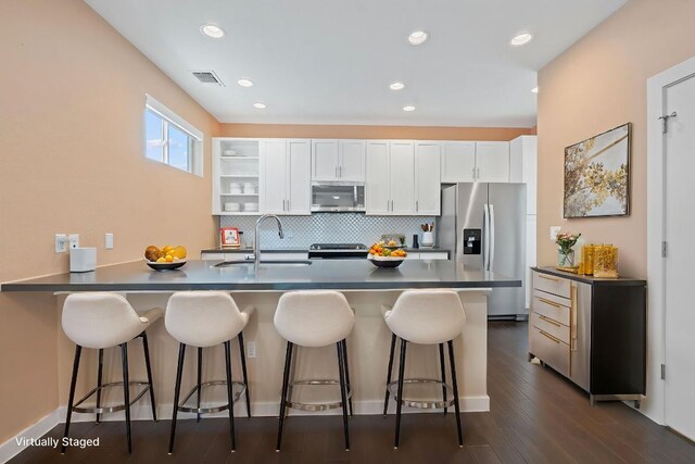 3105 Aldwyche Dr, Austin, TX 78704 - kitchen with stainless steel appliances, a sink, dark countertops, a peninsula, and white cabinets