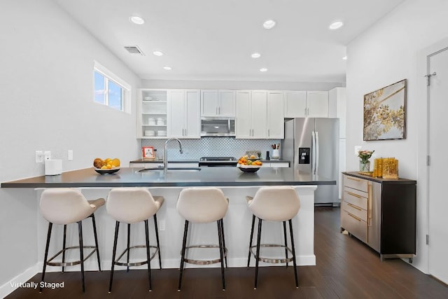 3105 Aldwyche Dr, Austin, TX 78704 - kitchen featuring appliances with stainless steel finishes, a sink, dark countertops, a peninsula, and white cabinetry