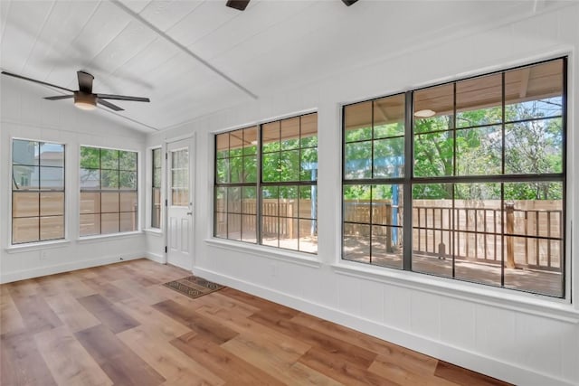 unfurnished sunroom with plenty of natural light, wood finished floors, lofted ceiling, and baseboards