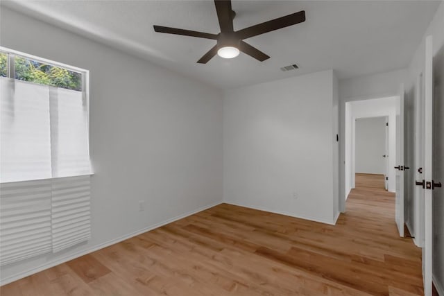 empty room with ceiling fan, light wood-style flooring, and baseboards